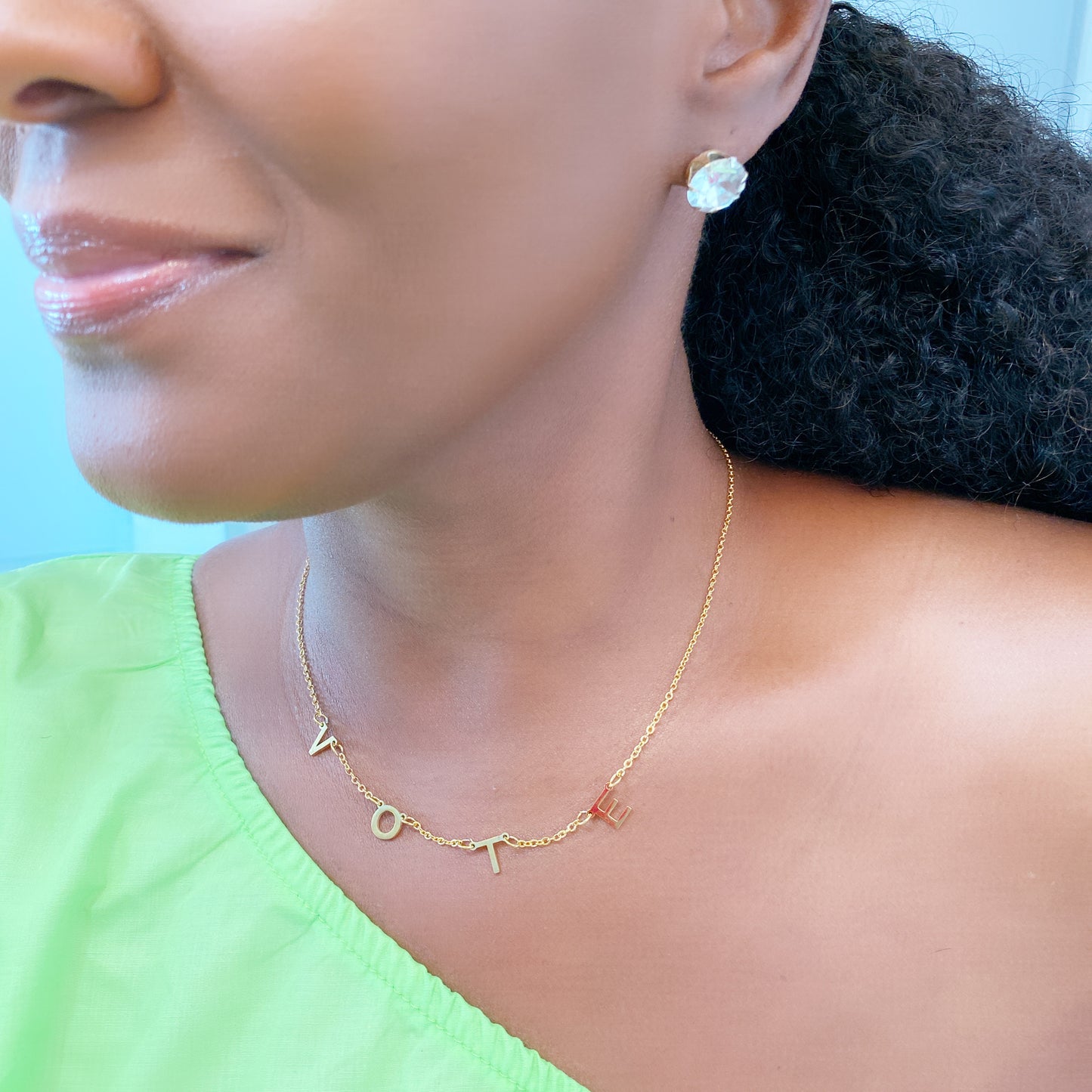 soror wearing gold stainless steel vote necklace with diamond earrings.