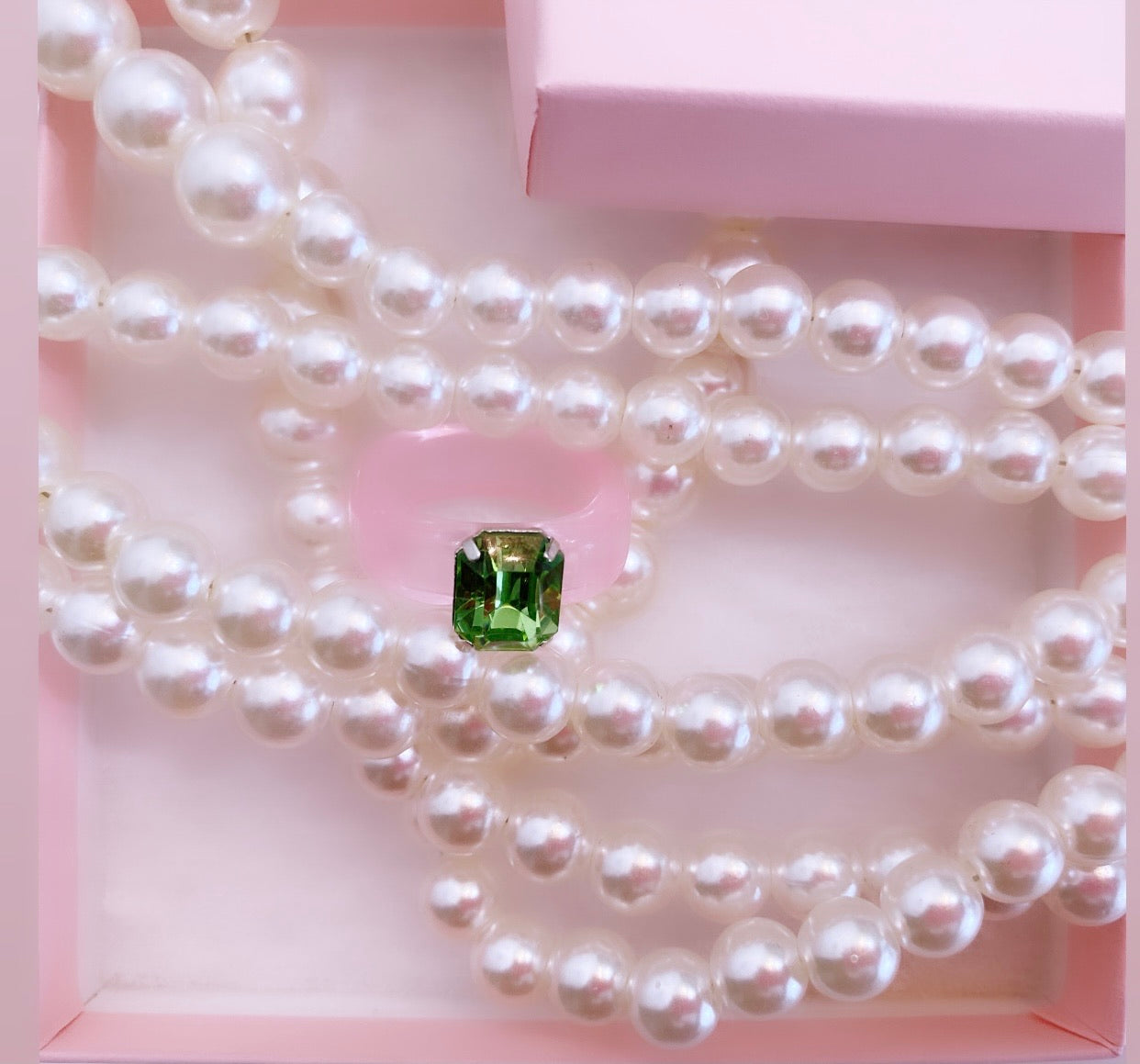 Green acrylic ring band with pink gem paired with a pearl necklace.